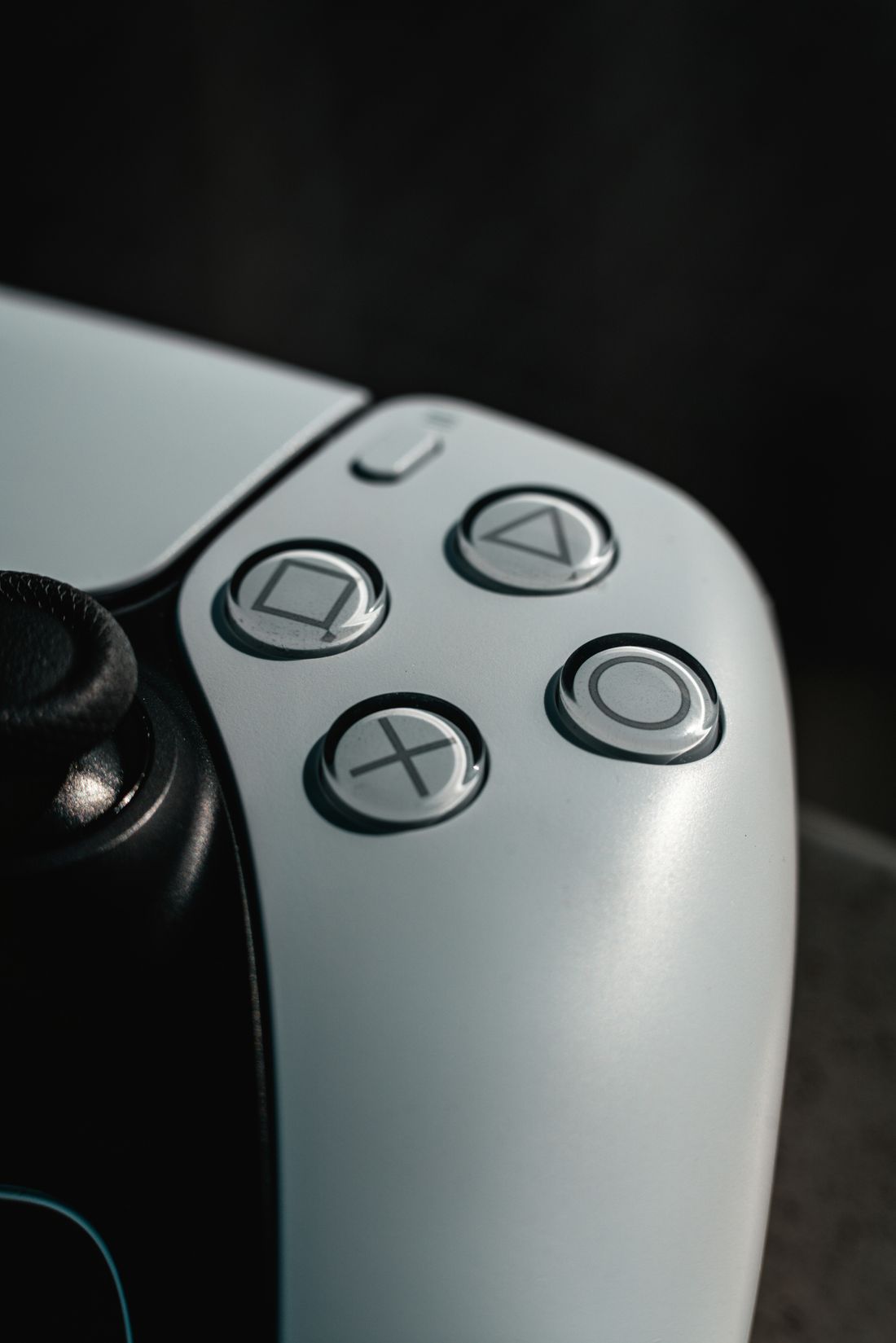 A DualSense controller emerging from shadow on a dark background